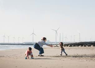 Family playing on beach with wind turbines in background