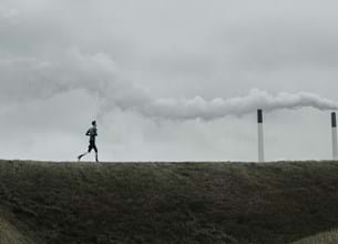 Man running in front of coal plant
